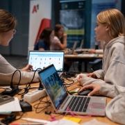 4 Mädchen arbeiten mit 2 Laptops an ihrem Digital Girls Hackathon Projekt