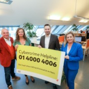 4 Personen halten Plakat mit Infos zur Cybercrime Helpline