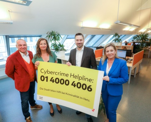 4 Personen halten Plakat mit Infos zur Cybercrime Helpline