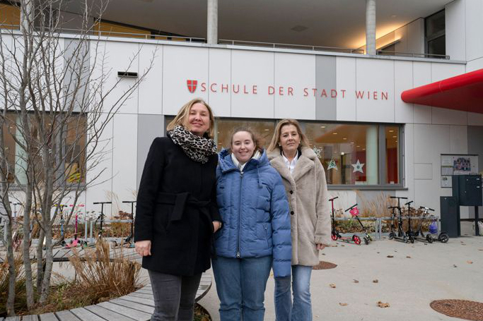 3 Frauen stehen vor einer Schule