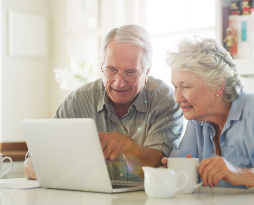 2 Senior*innen arbeiten am Laptop. Beide haben eine Tasse bei sich stehen.