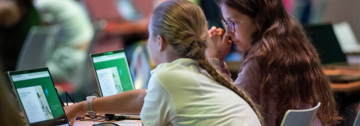 2 Mädchen sitzen vor Laptops