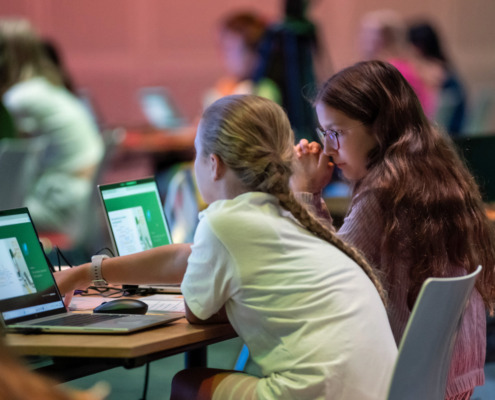 2 Mädchen sitzen vor Laptops