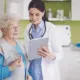 Ärztin und ältere Patientin blicken auf ein Tablet.