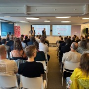 Gruppe von Menschen in Vortragssaal, 2 Vortragende, 2 große Bildschirme