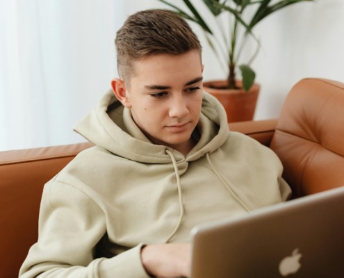 Jugendlicher auf Couch mit Laptop