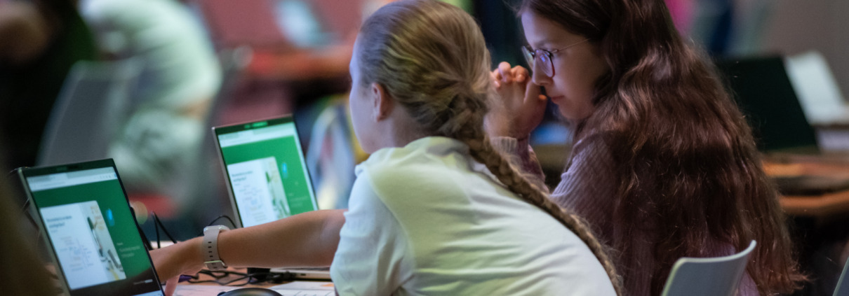 2 junge Mädchen sitzen vor ihren Laptops