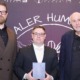 3 Männer vor einer Logowand halten eine Auszeichnung